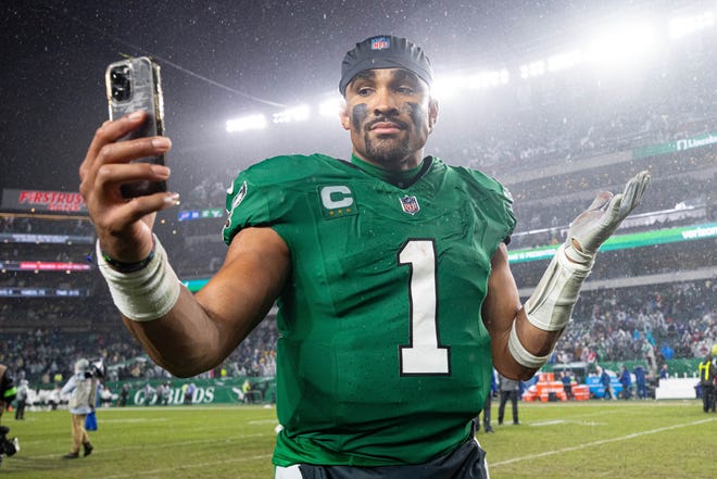 Philadelphia Eagles quarterback Jalen Hurts (1) reacts with a smartphone while walking off the field after an overtime victory against the Buffalo Bills at Lincoln Financial Field on Nov 26, 2023, in Philadelphia.