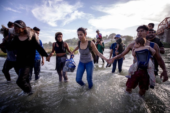 Migrants hold hands for safety as they cross the Rio Grande River into the U.S. in Eagle Pass, Texas on July 20, 2023, from Piedras Negras, Coahuila, Mexico. The migrants were part of a group of nearly 30 migrants who crossed hoping to seek asylum in the U.S.