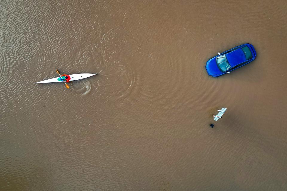 A canoeist paddles past a car abandoned in floodwater in Worcester city centre following Storm Henk (Getty Images)