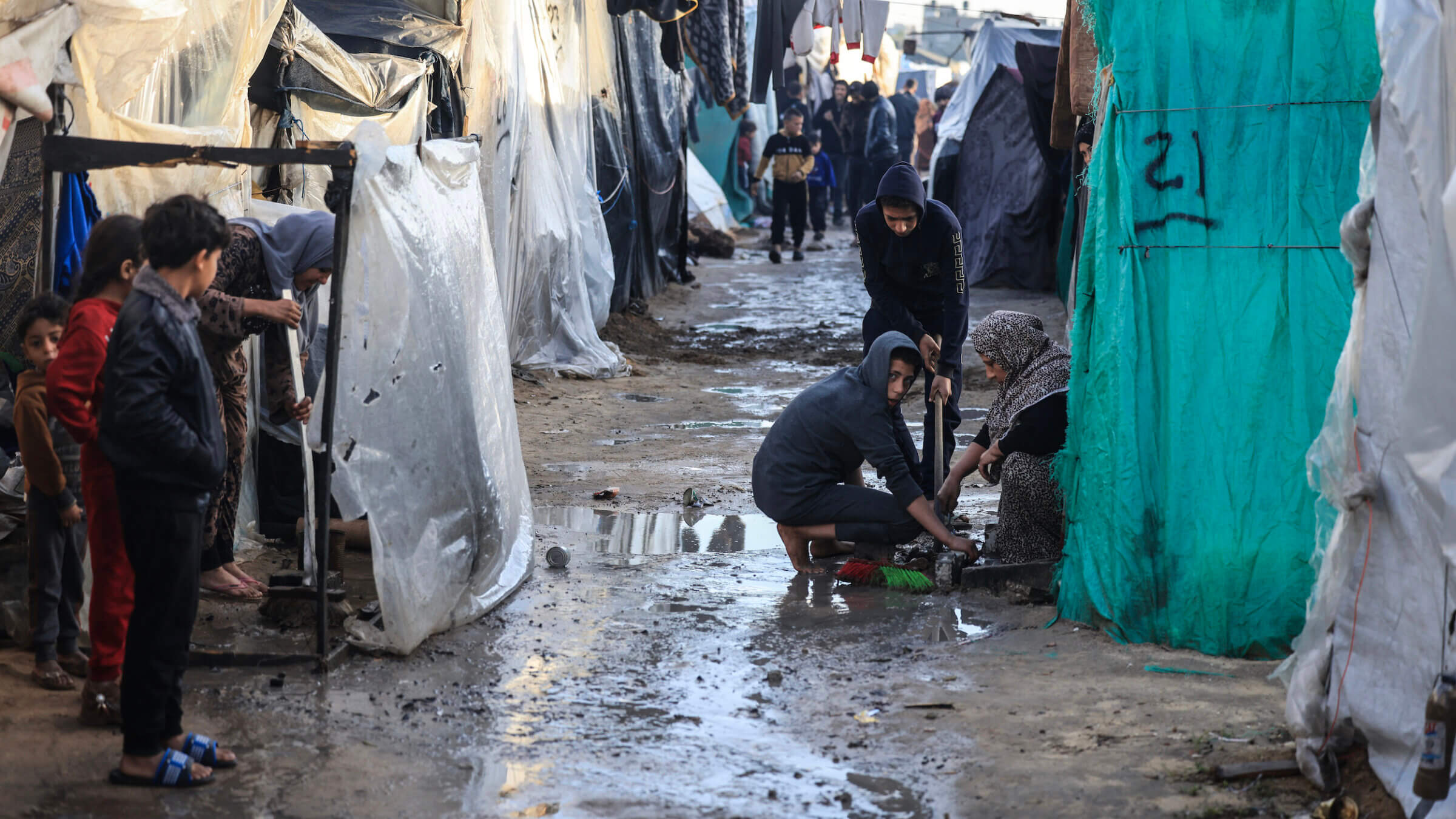 Displaced Palestinians in Gaza gather amid tents flooded by heavy rain, at a makeshift camp set up by people who fled the ongoing battles between Israel and Hamas.