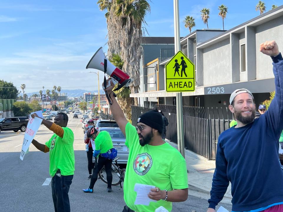 Drivers protest Uber, Lyft and DoorDash outside an Uber office in Los Angeles on Feb. 14, 2024. They were yelling in a bullhorn, blasting an air horn and chanting "Si, se puede" and "Drivers united will never be defeated." Passing cars were honking their horns in support.