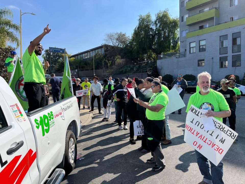 Drivers protest Uber, Lyft and DoorDash outside an Uber office in Los Angeles on Feb. 14, 2024. They were yelling in a bullhorn, blasting an air horn and chanting "Si, se puede" and "Drivers united will never be defeated."