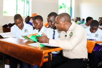 Ntakamaze Nziyonvira (right), working with refugee students in a classroom in Uganda. Photo courtesy of CIYOTA.