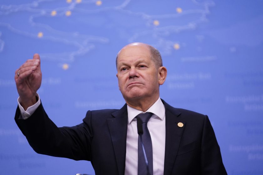 a picture of olaf scholz with his right hand in the air