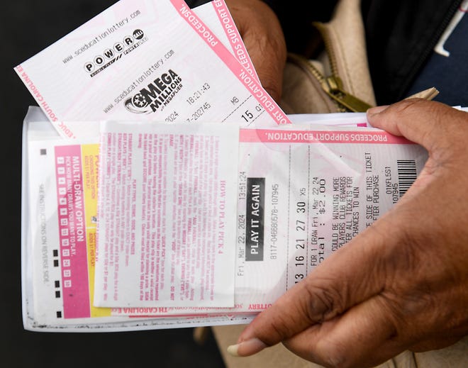 Kim Carson of Spartanburg, South Carolina holds Mega Millions and Powerball tickets outside of a store on Friday.