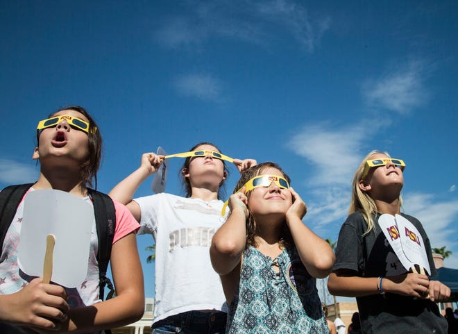 People watch the Aug. 21, 2017, solar eclipse with their protective glasses at Arizona State's Tempe campus. Proper protective eyewear is essential for safely viewing the upcoming eclipse on April 8.