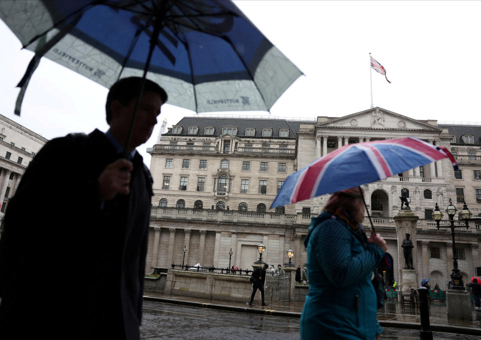 interest rates FILE PHOTO: A tourist shelters from the rain under an Union Jack umbrella near the Bank of England in the City of London financial district in London, Britain, February 13, 2024. REUTERS/Isabel Infantes/File Photo