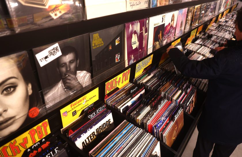 several rows of vinyl records in a store, person browsing them