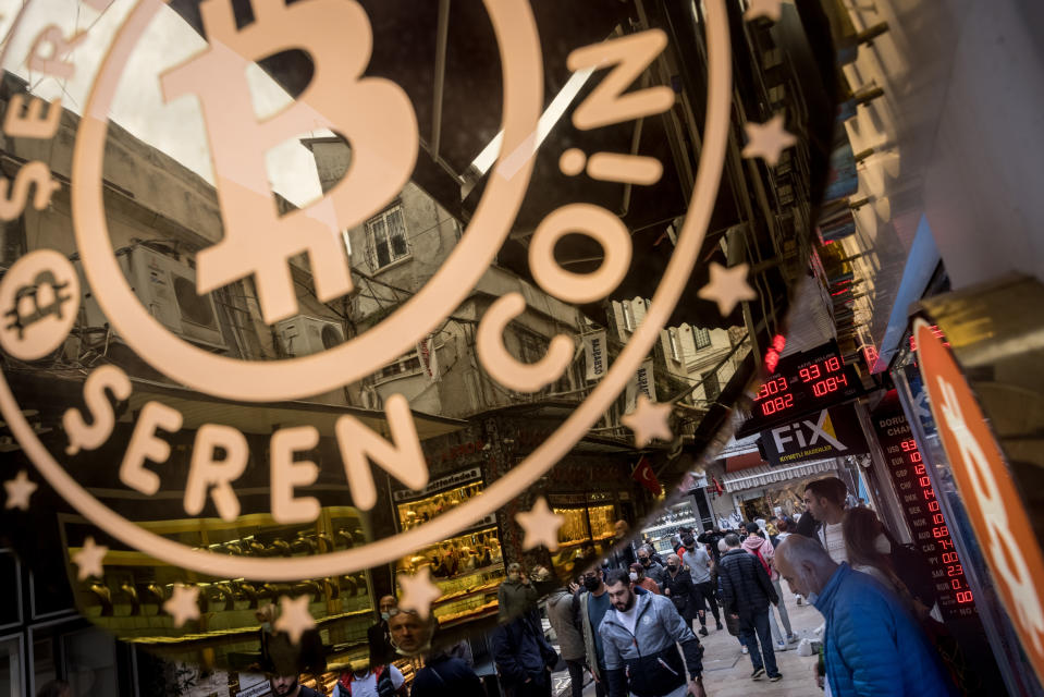 People walk on the street underneath a Bitcoin exchange office sign in Istanbul, Turkey.