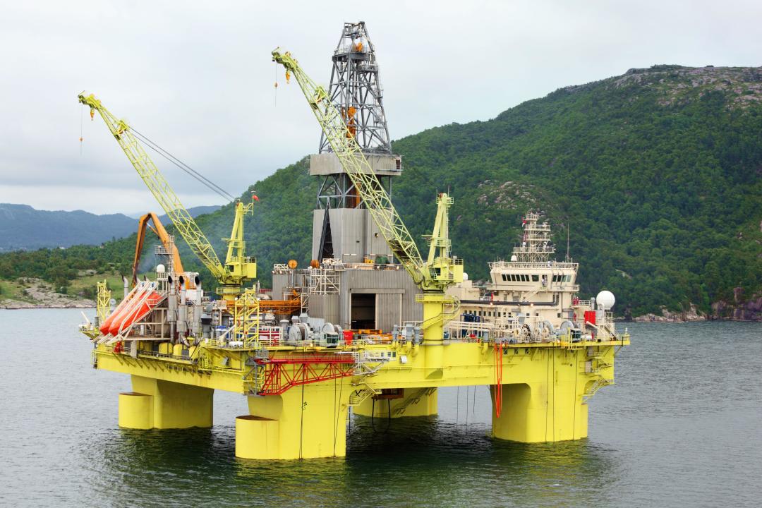 Ocean offshore oil rig drilling platform off near wooded shore of Stavanger, Norway.