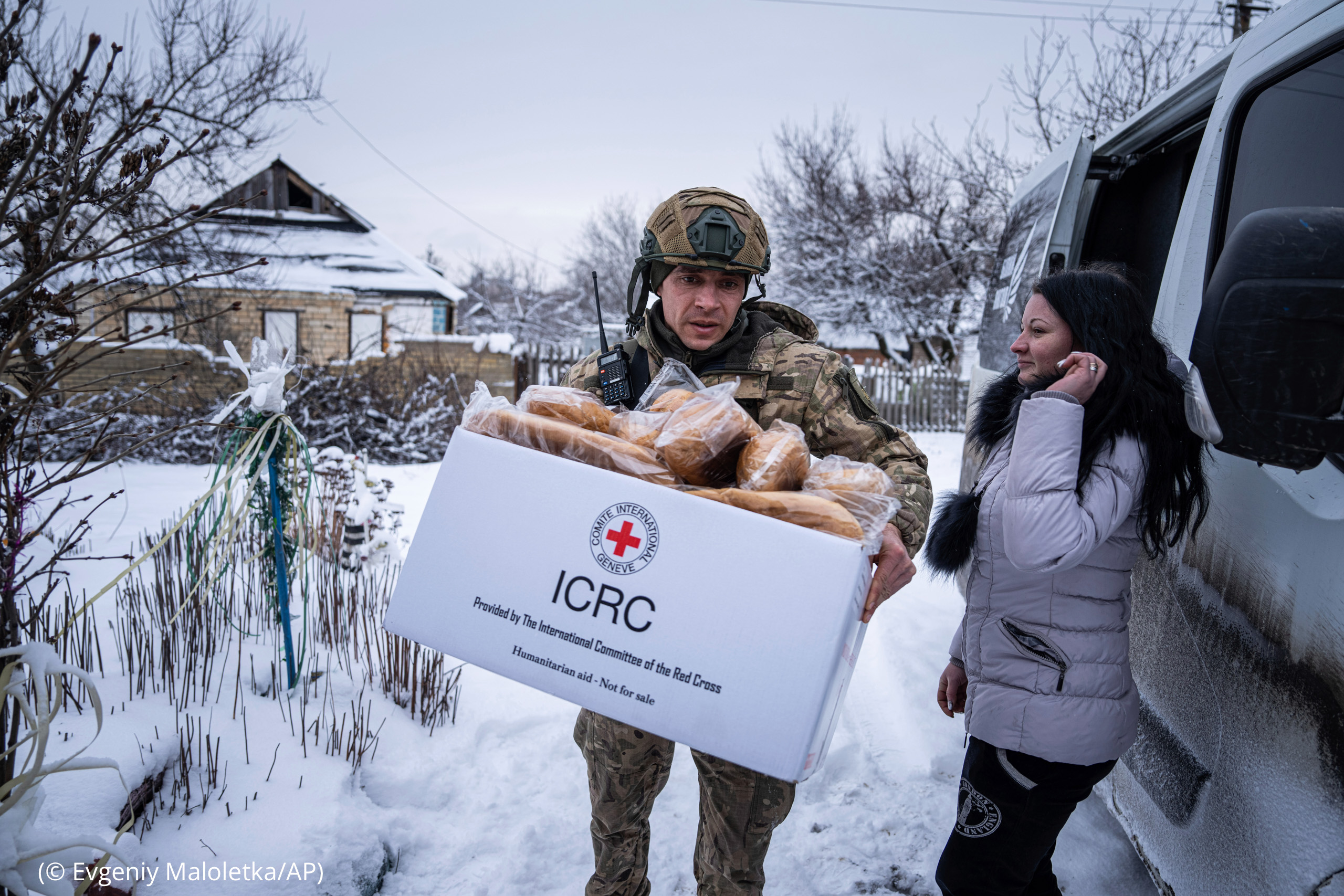 Man in uniform carrying filled box labeled 'ICRC' (© Evgeniy Maloletka/AP)