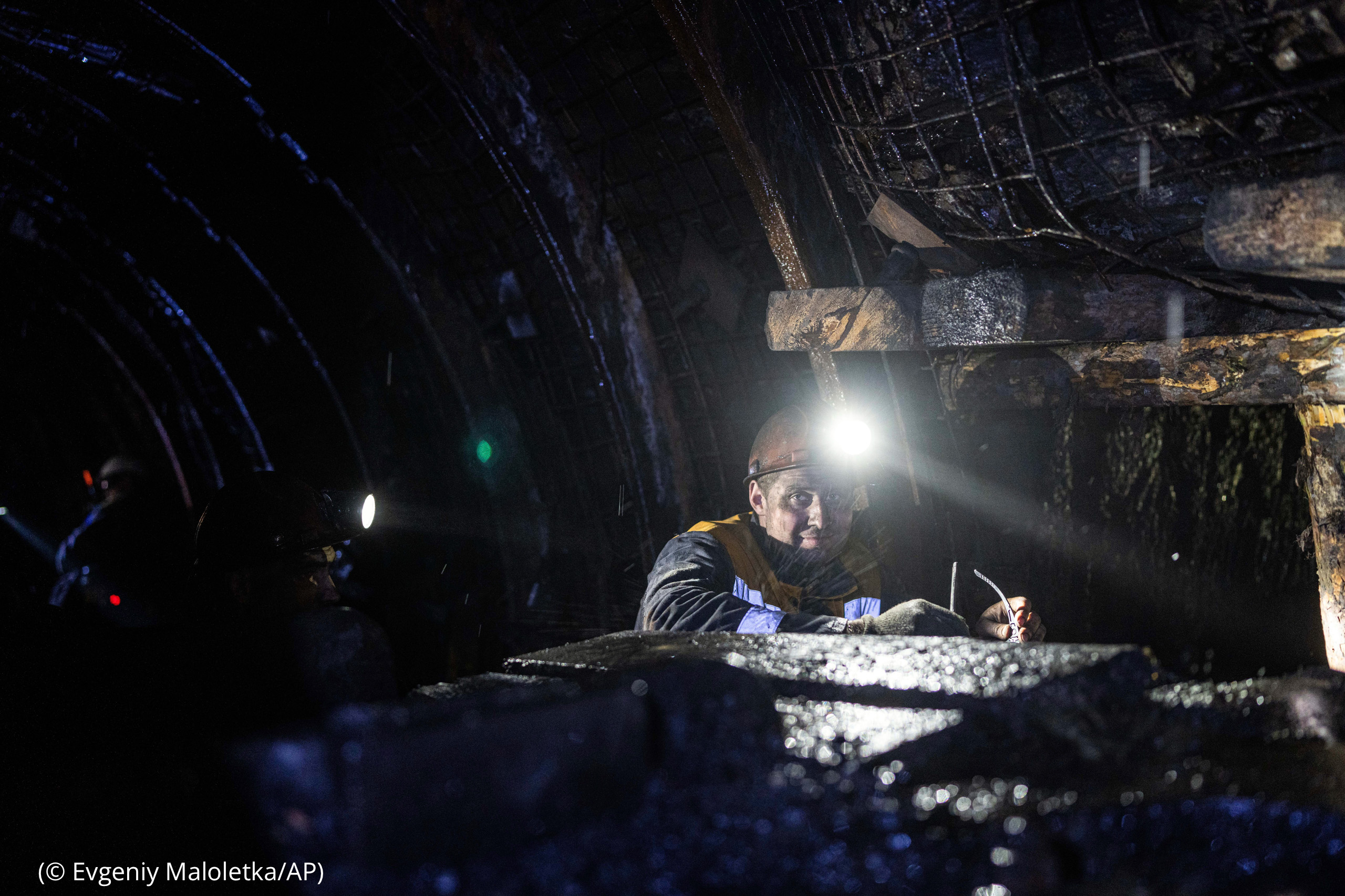 A coal miner with head light shining (© Evgeniy Maloletka/AP)