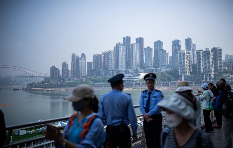 Passers-by and tourists stand on the banks of the Yangtze River in Chongqing, China. FTSE, European stocks