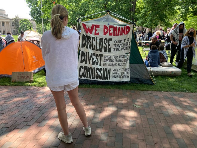 An onlooker reads a list of demands from pro-Palestinian student protesters at an encampment at the University of North Carolina on April 26, 2024. On April 30, protesters replaced a prominent American flag flying in the quad with a Palestinian flag.