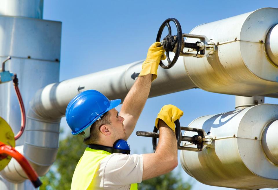 A person turning valves on an energy pipeline.
