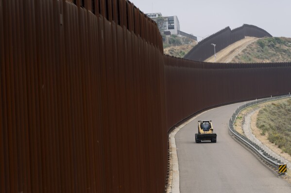 A construction worker drive along the border walls separating Tijuana, Mexico, from the United States, Tuesday, June 4, 2024, in San Diego. President Joe Biden has unveiled plans to enact immediate significant restrictions on migrants seeking asylum at the U.S.-Mexico border as the White House tries to neutralize immigration as a political liability ahead of the November elections. (AP Photo/Gregory Bull)