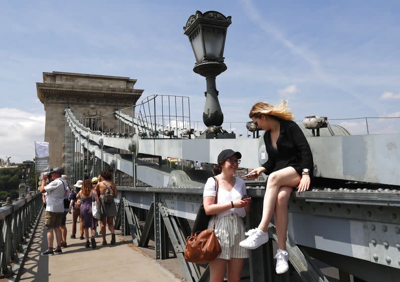 Tourists and Hungarians walk on the Chain Bridge over the Danube River in Budapest, June 2019