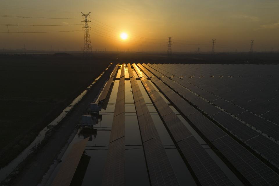 The sun sets over electric pylons along a solar farm near Weifang in eastern China's Shandong province on March 22, 2024. Chinese battery companies, EV manufacturers and utilities are all racing to develop more advanced batteries to store the electricity from solar panels. (AP Photo/Ng Han Guan)