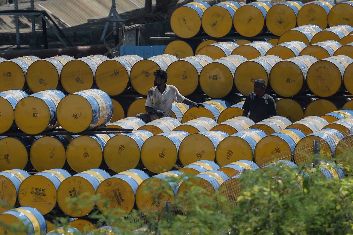 Workers stack oil barrels at a filling station in Chennai, India.