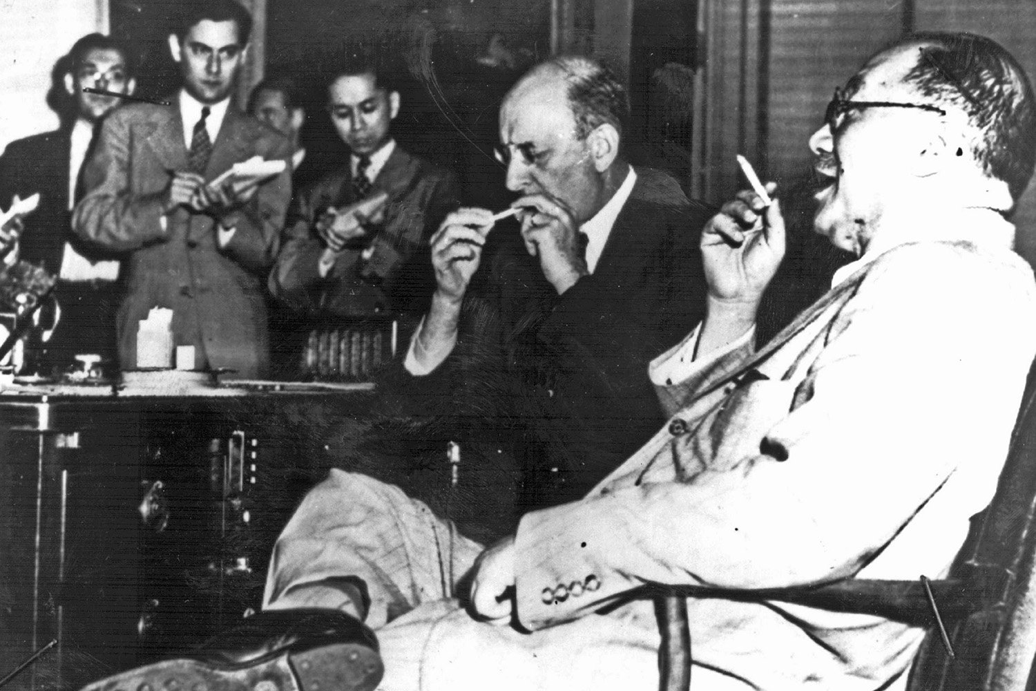 U.S. Treasury Secretary Henry Morgenthau and Chinese Vice Premier H.H. Kung sit next to each other, smoking, as men take notes in the background, at the Bretton Woods Conference in 1944.