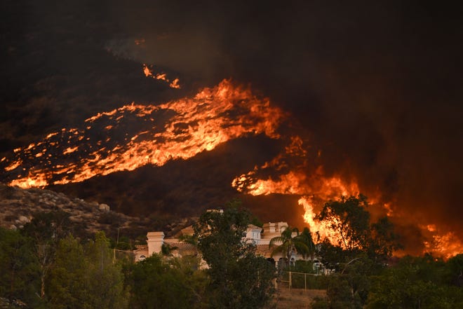 Plumes of smoke rise as wildfire approaches a home during the Fairview Fire near Hemet, California in Riverside County on September 7, 2022. - A ferocious heat wave scorching the western United States could finally begin to wane in the coming days, forecasters said on September 7, but they warned of dangerous fire conditions as howling winds sweep through the bone-dry region. (Photo by Patrick T. FALLON / AFP) (Photo by PATRICK T. FALLON/AFP via Getty Images)