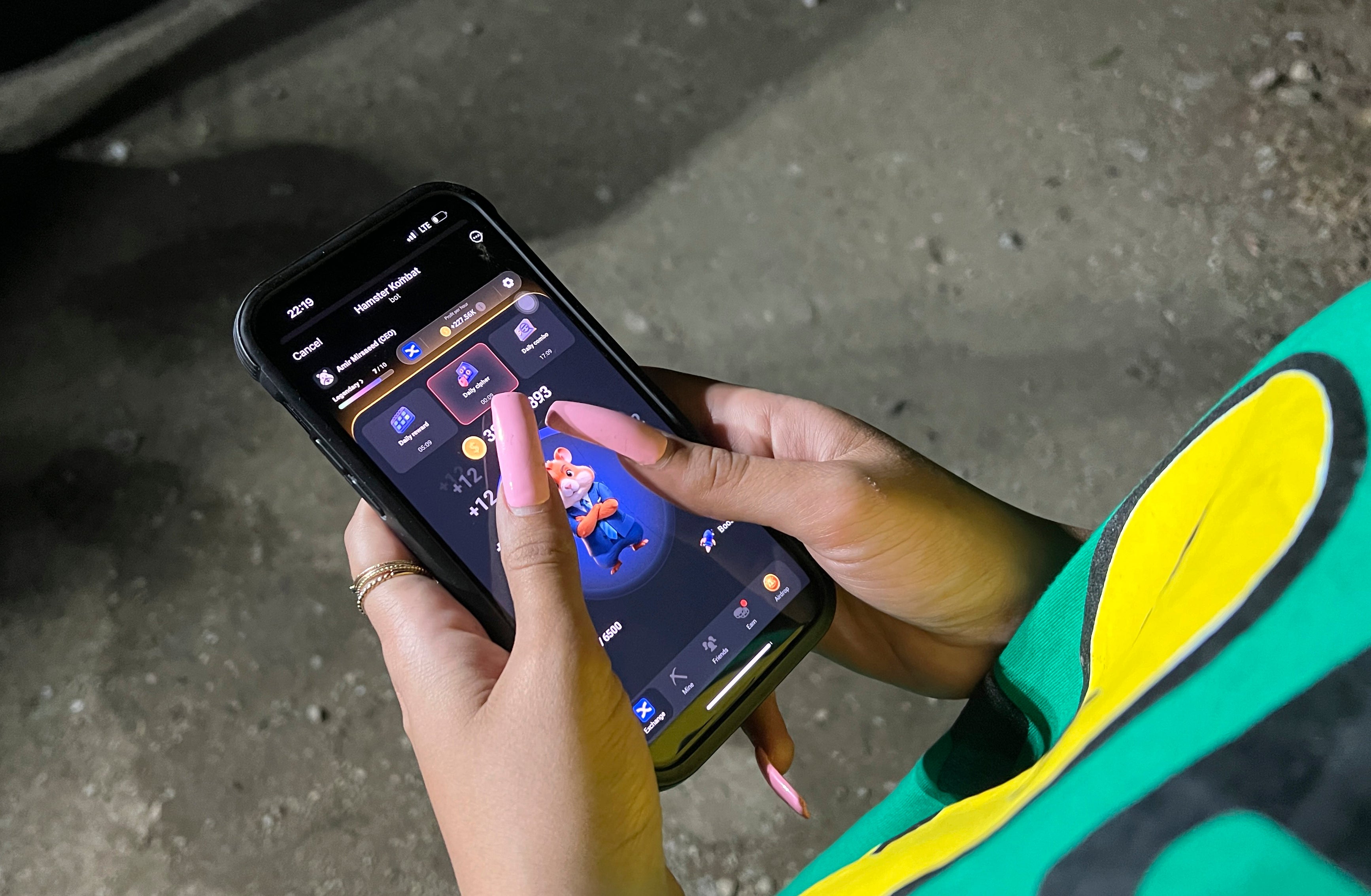 A woman plays Hamster Combat game on a cell phone in Tehran, Iran