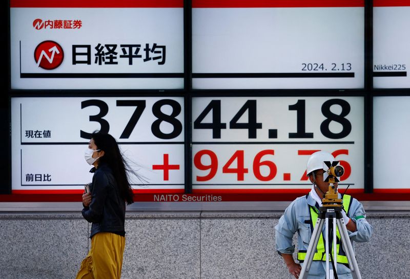 © Reuters. FILE PHOTO: Passersby walk past in front of an electric screen displaying Japan's Nikkei share average outside a brokerage in Tokyo, Japan February 13, 2024.  REUTERS/Issei Kato/file photo