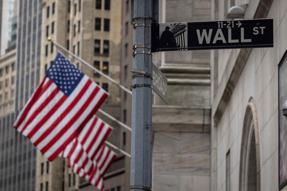 The sign for Wall Street is seen with US flags outside the New York Stock Exchange in New York on June 16, 2022. (Photo by Yuki IWAMURA / AFP) (Photo by YUKI IWAMURA/AFP via Getty Images)