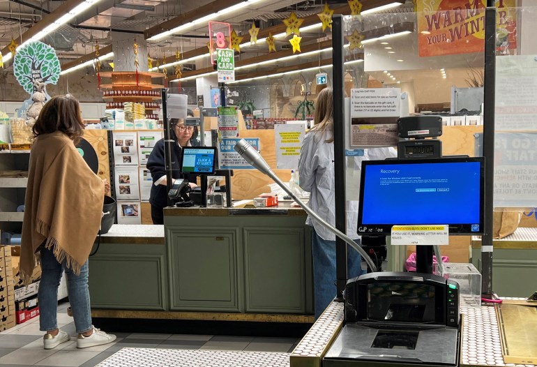 A cash register shows a blue screen at a grocery store affected by a cyber outage in Sydney, Australia