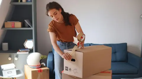 Getty Images Woman packing up boxes as she prepares to move house