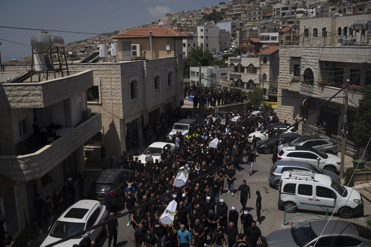 Mourners carry the coffins of some of the 12 children and teens killed in a rocket strike at a football pitch in the Israeli-occupied Golan Heights, Sunday, July 28, 2024.