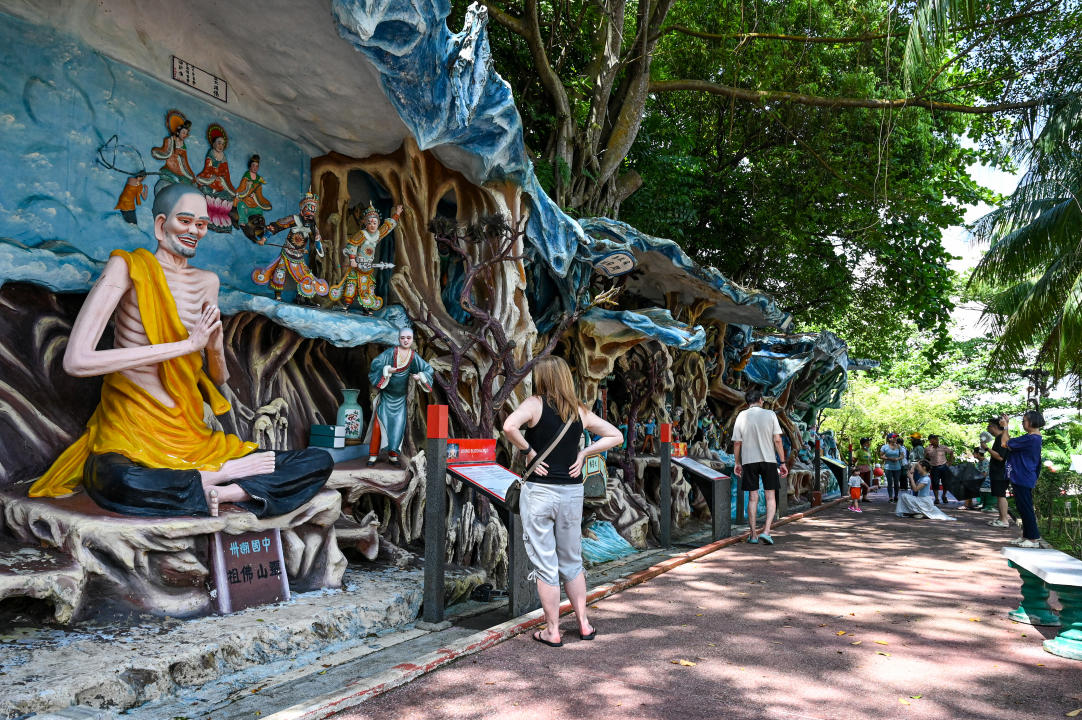 This photo taken on May 1, 2024 shows visitors walking past statues at Haw Par Villa, an Asian cultural park that features Chinese folklore, legend and mythology in Singapore.